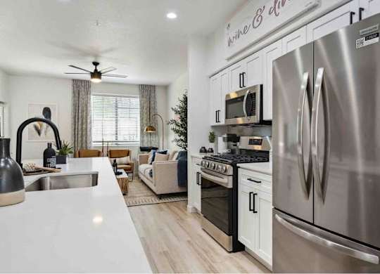 A modern kitchen with a stainless steel refrigerator and a dining area with a couch and chairs.