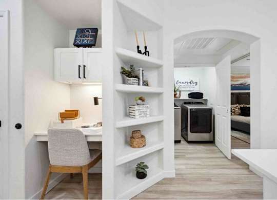 A white room with a desk and a shelf.