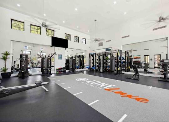 A gym with a variety of equipment and a large mirror on the wall.