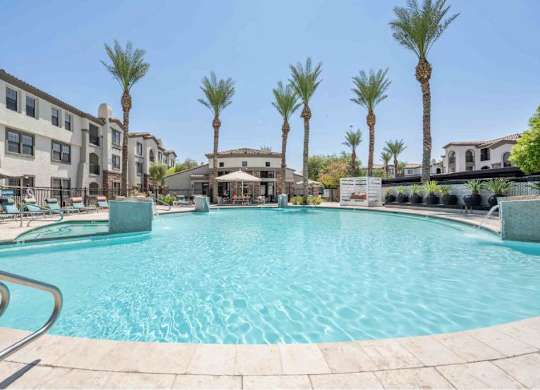 A large swimming pool surrounded by palm trees and apartment buildings.