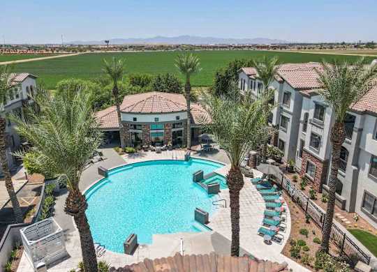A swimming pool surrounded by palm trees and apartment buildings.
