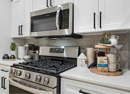 A modern kitchen with a stainless steel stove and a microwave above it.