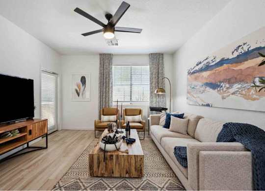 A living room with a flat screen TV, a wooden coffee table, and a large painting on the wall.