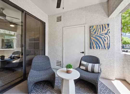 A living room with a grey chair, a white table, and a painting on the wall.