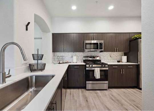 A modern kitchen with dark wood cabinets and stainless steel appliances.