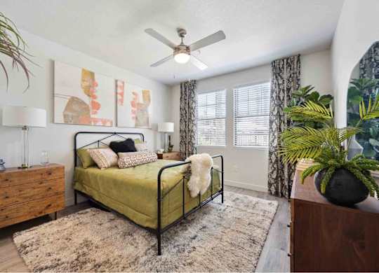 A bedroom with a bed, dresser, and a ceiling fan.