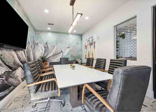 A conference room with a large table surrounded by chairs.