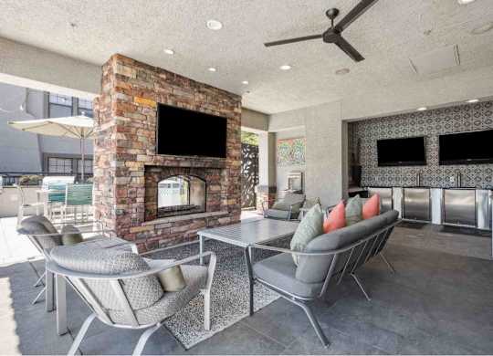 A modern outdoor patio with a stone fireplace and seating area.