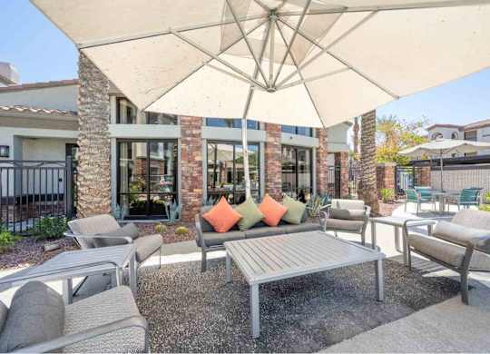 A patio with a table and chairs under a large umbrella.