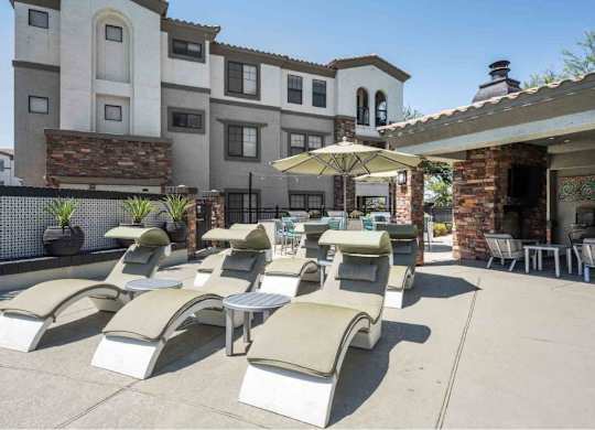 A row of sun loungers are arranged on a patio in front of a building.