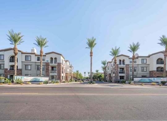 A row of apartment buildings with palm trees in front.