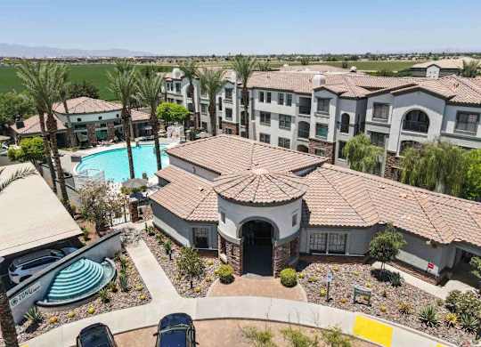 A large building with a pool and palm trees in front.