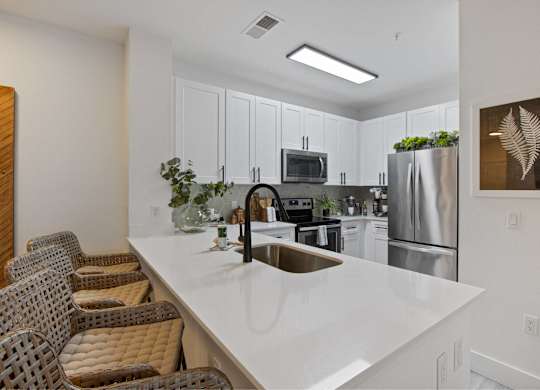 a kitchen with a white counter top and a stainless steel refrigerator