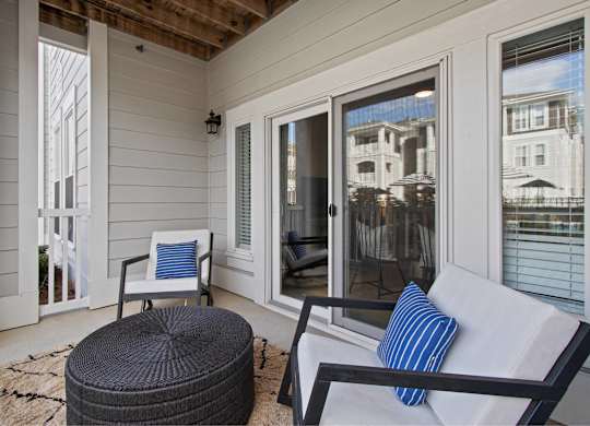 a covered porch with two chairs and a table