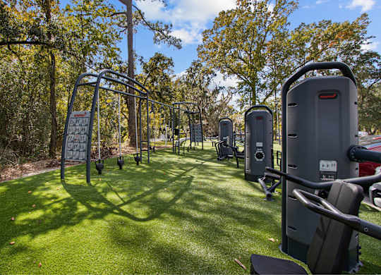 a group of exercise equipment on the grass at a park