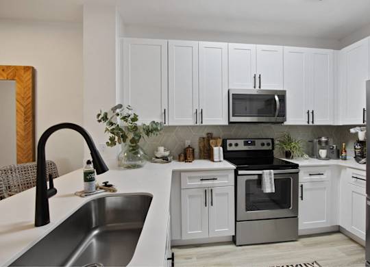 a white kitchen with stainless steel appliances and white cabinets