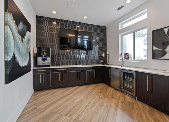 a kitchen with wood floors and black cabinets and a tv