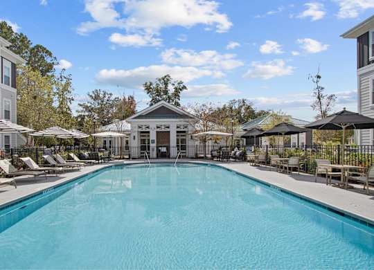a swimming pool with chairs and umbrellas in front of a building