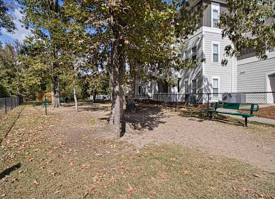 a park with a bench and trees in front of a building
