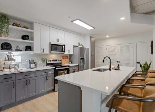 A modern kitchen with a white countertop and grey cabinets.