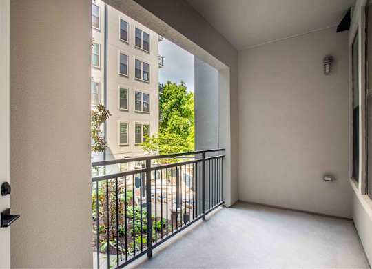 A balcony with a black railing and a view of a building and trees.