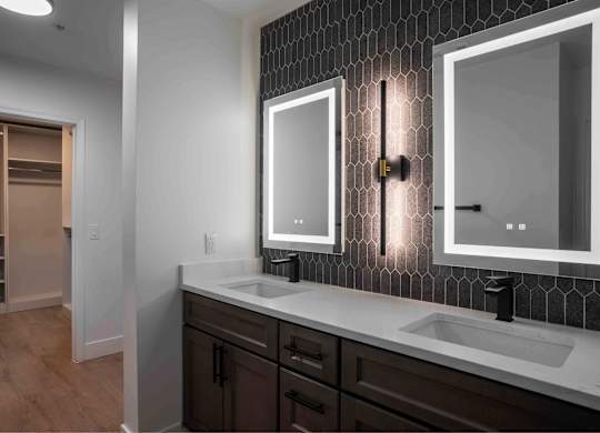 A bathroom with a sink, mirror, and wooden floors.