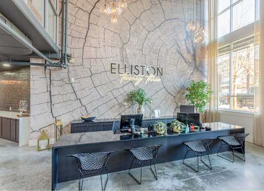 A reception area with a large table and chairs in front of a wall with a tree ring pattern and the word