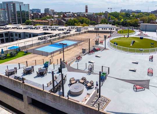 A rooftop with a pool, loungers, and a green space.