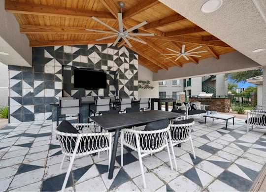 A patio with a table and chairs under a wooden ceiling.
