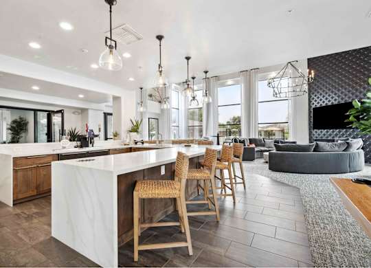 Clubhouse kitchen with a large center island next to a living room with a couch and a fireplace