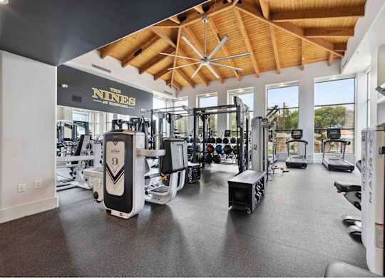 a spacious fitness center with cardio equipment and large windows