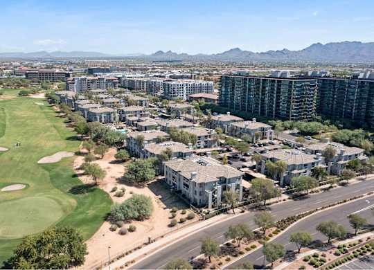 an aerial view of apartments and a golf course with mountains in the background