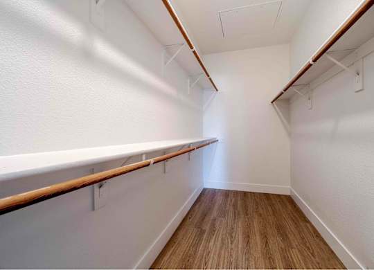 a spacious walk in closet with a wood floor and white walls
