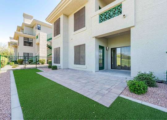 a patio in front of a building with green grass