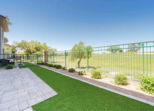 a backyard with green grass and a fence