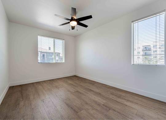 an empty living room with wood floors and a ceiling fan