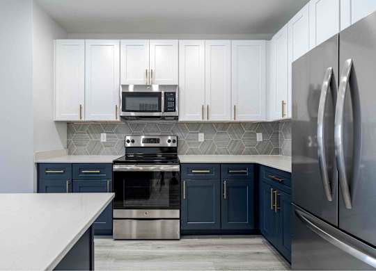 a kitchen with blue and white cabinets and stainless steel appliances