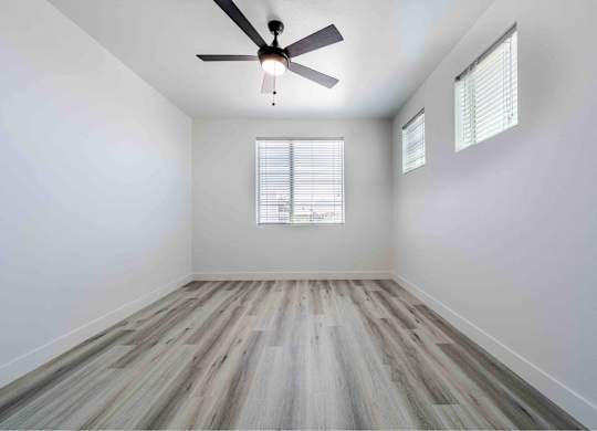 an empty room with wood floors and a ceiling fan
