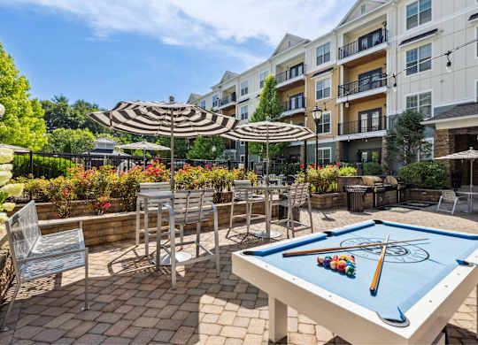 A pool table is set up on a patio with a pool cue and balls on it.