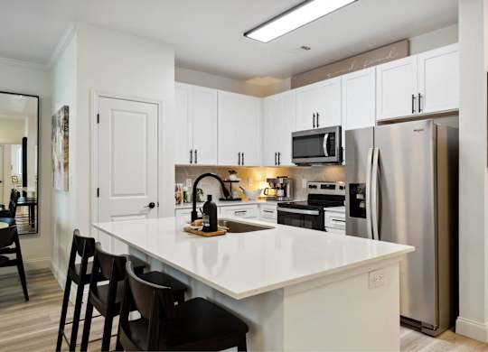 A kitchen with white cabinets and a white island.