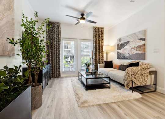 A living room with a couch, a coffee table, and a ceiling fan.