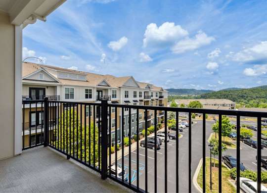 A balcony overlooks a parking lot and buildings.
