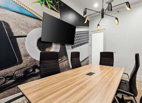 A conference room with a wooden table and black chairs.
