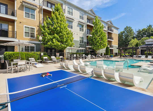 A blue ping pong table is in the middle of a pool area.