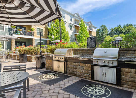 A patio with a grill and umbrella.