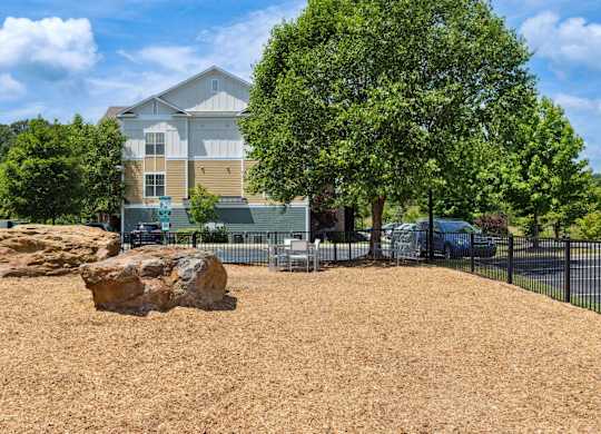 A large rock sits in the middle of a mulched area in front of a house.