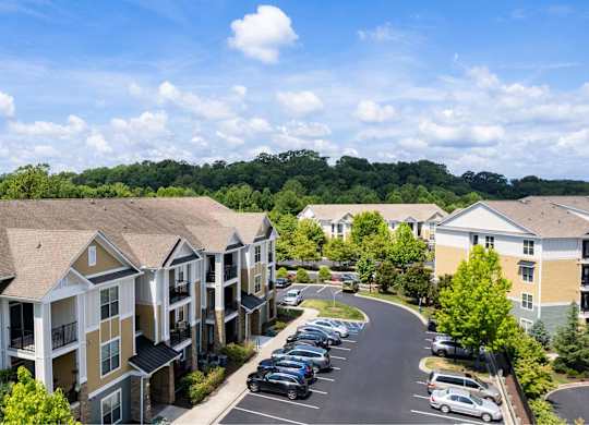 A sunny day at a residential complex with cars parked in the lot.