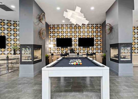 A pool table is in the middle of a room with a black and gold patterned wall.