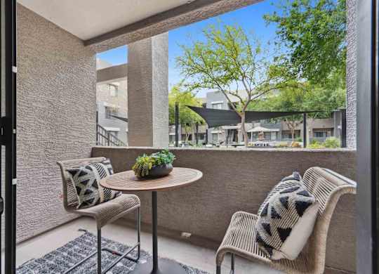 A patio with a table and two chairs with a view of apartment buildings.