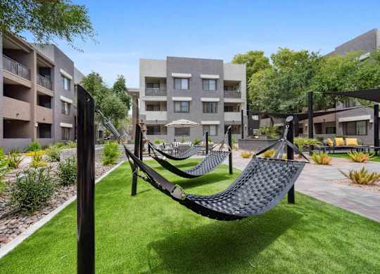 A black hammock is suspended between two poles in a grassy area.